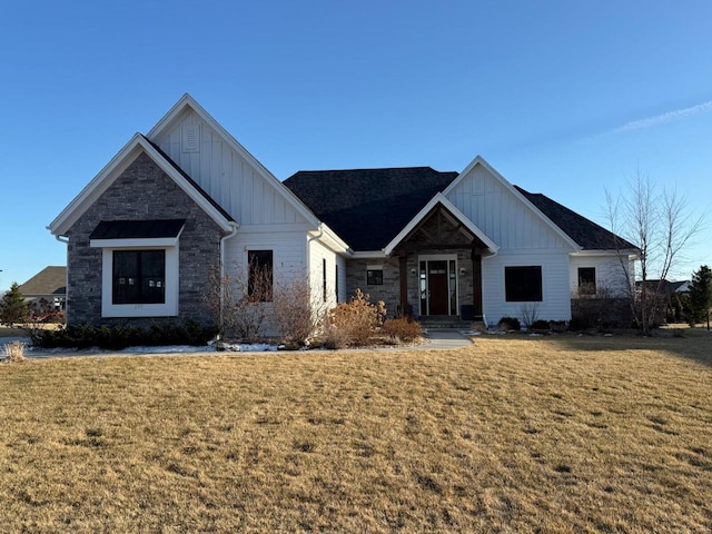 view of front of home featuring board and batten siding, stone siding, and a front lawn