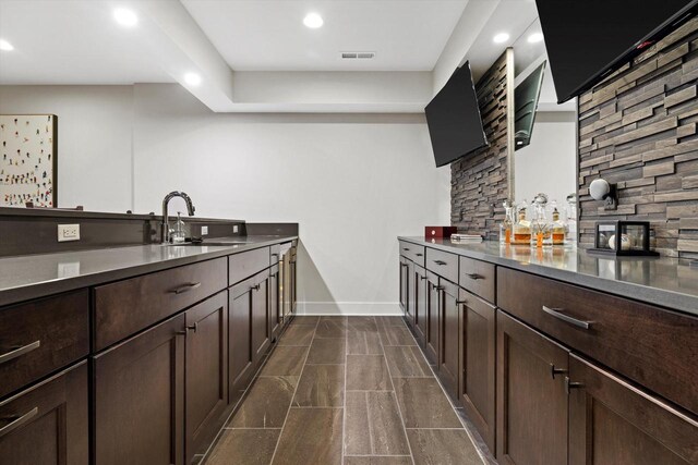 kitchen featuring baseboards, recessed lighting, dark brown cabinets, visible vents, and a sink