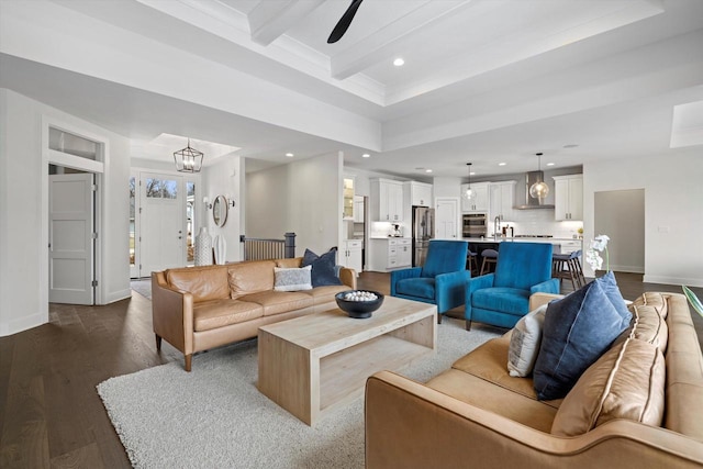 living room featuring baseboards, recessed lighting, dark wood-type flooring, beam ceiling, and ceiling fan with notable chandelier