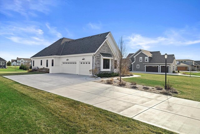 view of side of home featuring an attached garage, stone siding, a lawn, concrete driveway, and a residential view