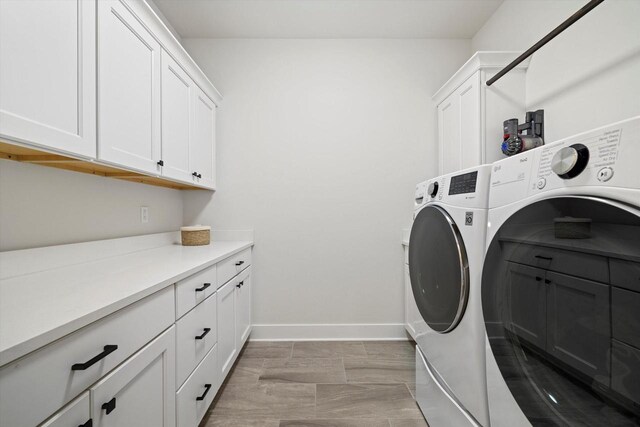 washroom with cabinet space, baseboards, and washing machine and dryer