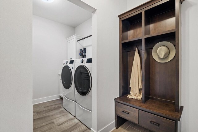 laundry area featuring light wood-style flooring, baseboards, washing machine and clothes dryer, and cabinet space
