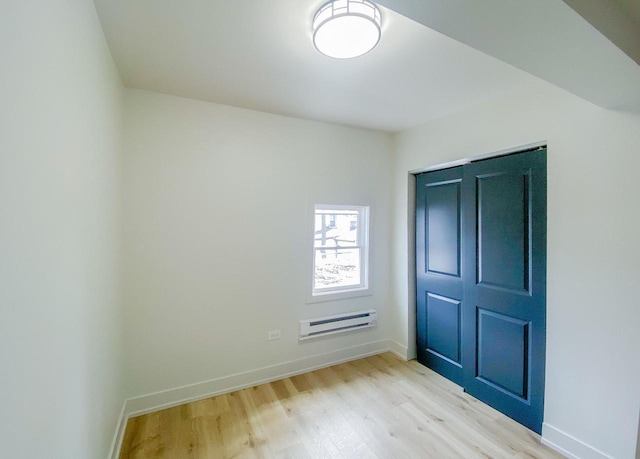 unfurnished bedroom with baseboards, wood finished floors, and a wall mounted air conditioner