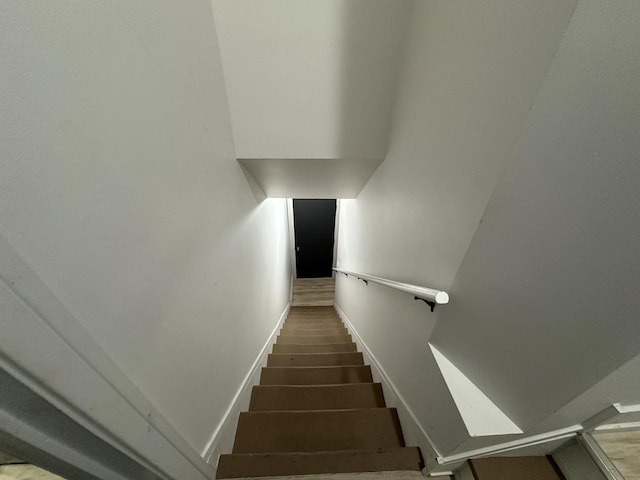 staircase featuring baseboards and wood finished floors