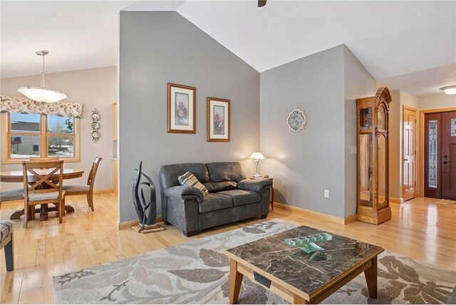 living room featuring baseboards, wood finished floors, and lofted ceiling
