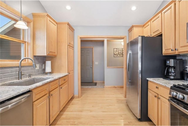 kitchen featuring a sink, appliances with stainless steel finishes, light brown cabinetry, light wood finished floors, and decorative backsplash