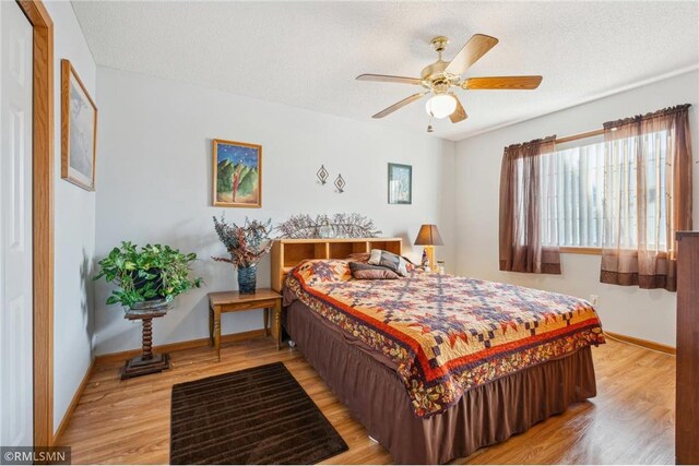 219 Bluff Dr, Somerset, WI 54025 - bedroom featuring light wood-style flooring, a ceiling fan, baseboards, and a textured ceiling