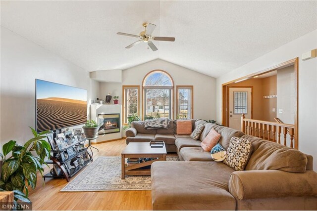 219 Bluff Dr, Somerset, WI 54025 - living room featuring ceiling fan, a glass covered fireplace, light wood-style floors, and lofted ceiling