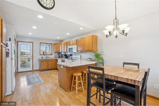 219 Bluff Dr, Somerset, WI 54025 - kitchen with light countertops, white appliances, a chandelier, a peninsula, and light wood-style flooring