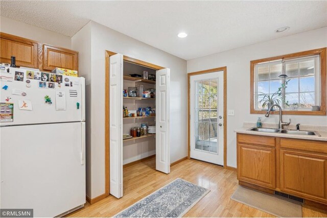 219 Bluff Dr, Somerset, WI 54025 - kitchen with light countertops, freestanding refrigerator, visible vents, light wood finished floors, and a sink