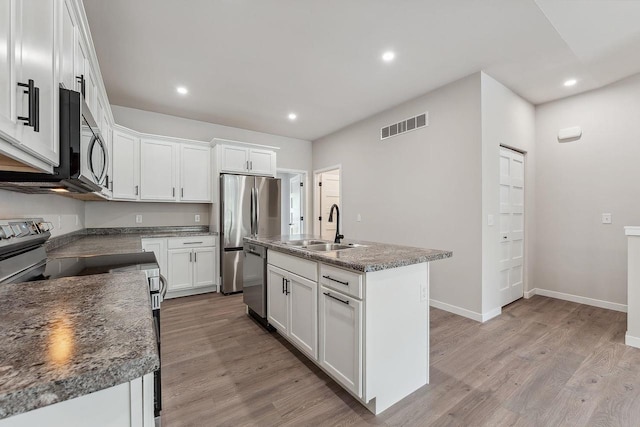 216 S Dewey Ave, Reedsburg, WI 53959 - kitchen with a sink, stainless steel appliances, light wood-type flooring, recessed lighting, and white cabinetry