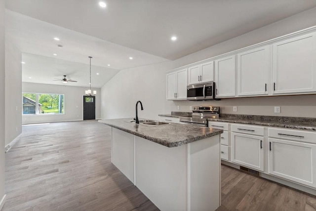 216 S Dewey Ave, Reedsburg, WI 53959 - kitchen featuring appliances with stainless steel finishes, a sink, vaulted ceiling, light wood finished floors, and white cabinetry