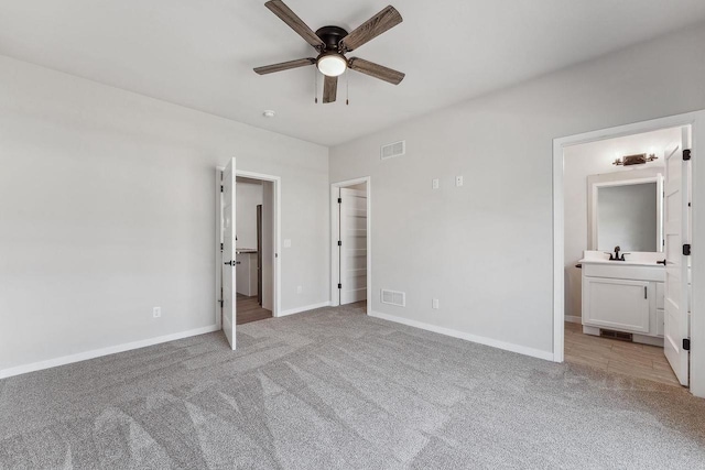 216 S Dewey Ave, Reedsburg, WI 53959 - unfurnished bedroom featuring light colored carpet, baseboards, a sink, ensuite bathroom, and a spacious closet