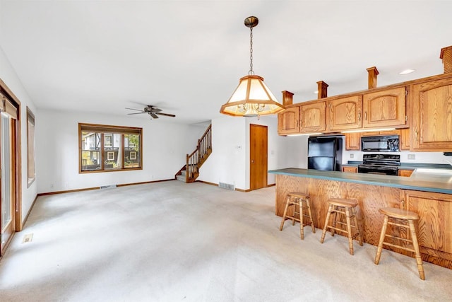 W8547 Cloverleaf Lake Rd, Clintonville, WI 54929 - kitchen featuring black appliances, light carpet, a breakfast bar area, a peninsula, and decorative light fixtures