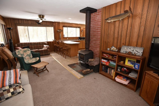 W1514 Spirit Ridge Trl, Keshena, WI 54135 - living room with a wood stove, wooden walls, light colored carpet, and a ceiling fan
