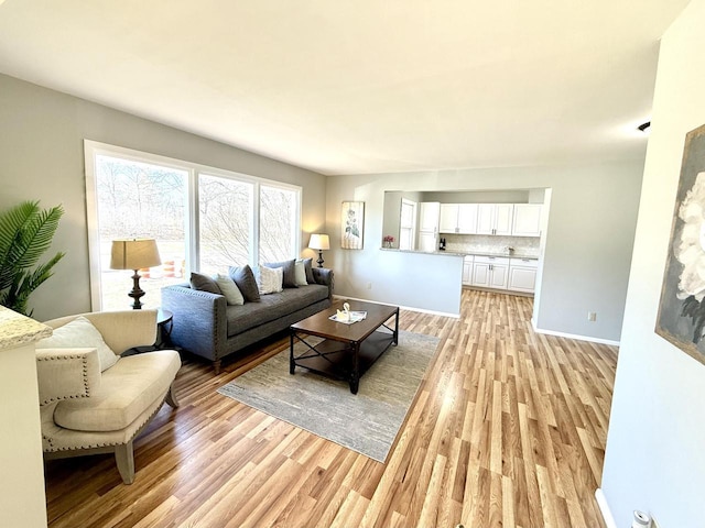 living area featuring light wood-style floors and baseboards