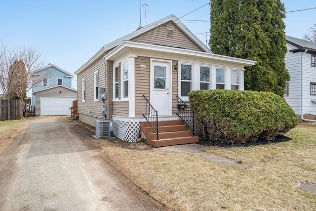 view of front facade featuring entry steps, a detached garage, an outdoor structure, central air condition unit, and driveway