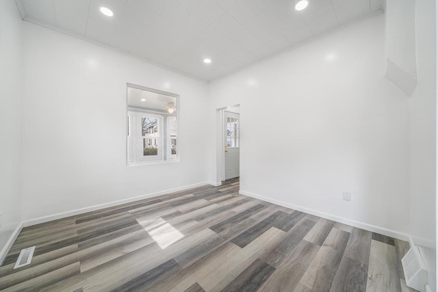 spare room featuring wood finished floors, baseboards, visible vents, and recessed lighting