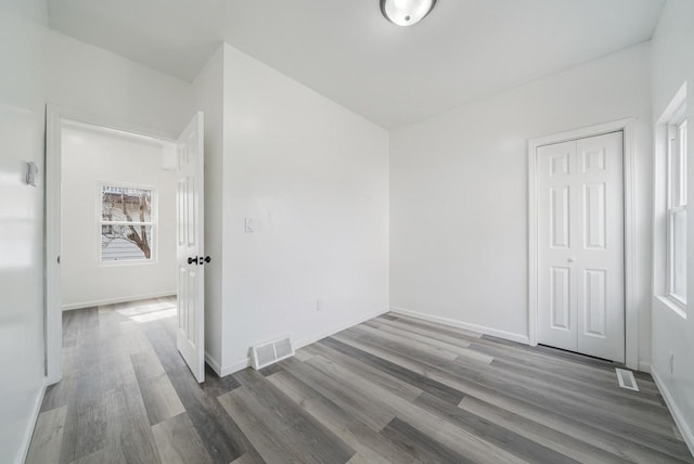 unfurnished bedroom with visible vents, baseboards, a closet, and wood finished floors