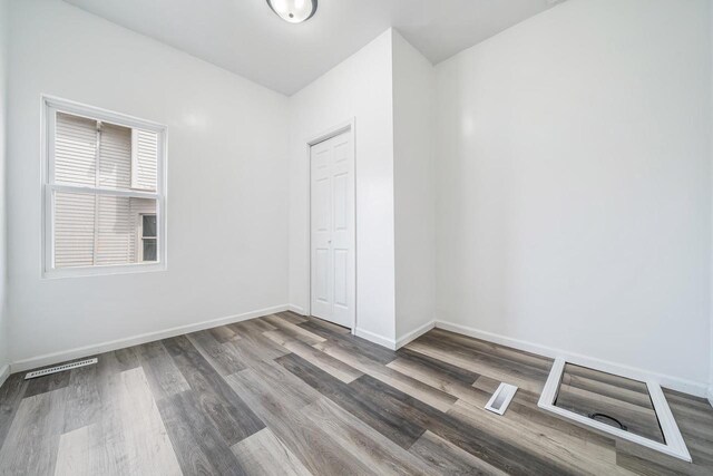 empty room featuring visible vents, baseboards, and wood finished floors