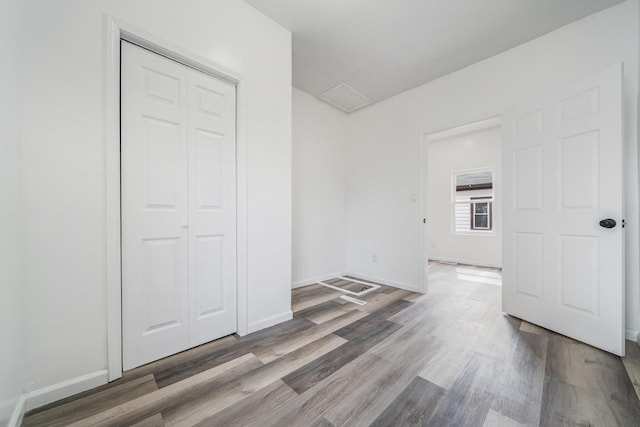unfurnished bedroom featuring a closet, baseboards, and wood finished floors