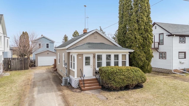 view of front of home with roof with shingles, an outdoor structure, driveway, entry steps, and fence