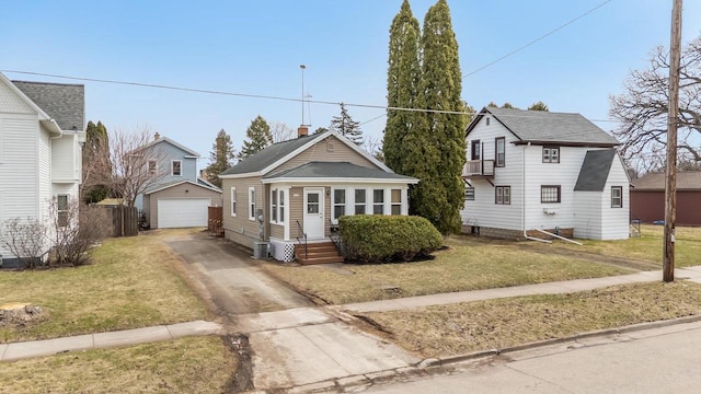 view of front of home featuring a front yard, a detached garage, fence, an outbuilding, and driveway