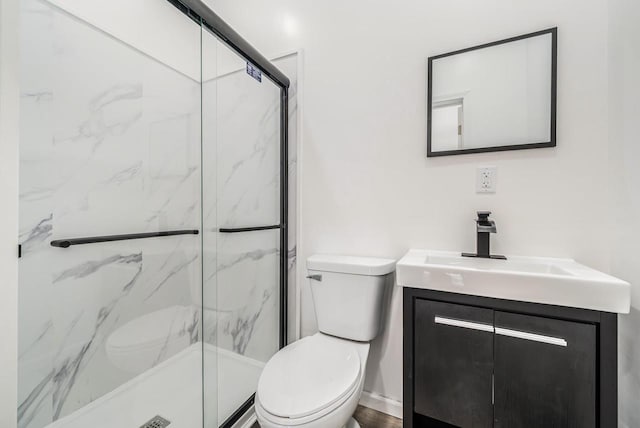 bathroom featuring vanity, a marble finish shower, and toilet