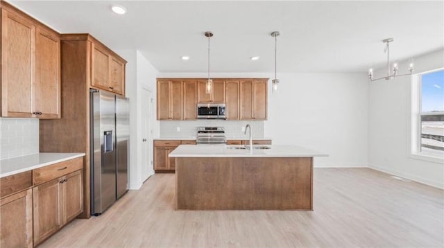 1517 Creekwood Dr, New Richmond, WI 54017 - kitchen with stainless steel appliances, a sink, light wood-style flooring, tasteful backsplash, and brown cabinetry