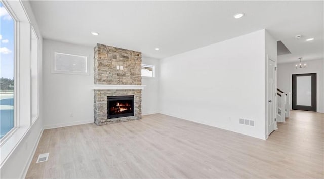 1517 Creekwood Dr, New Richmond, WI 54017 - unfurnished living room featuring light wood-style flooring, stairs, a stone fireplace, recessed lighting, and a chandelier