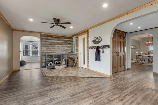 8283 345th St, Stanley, WI 54768 - unfurnished living room featuring ceiling fan, arched walkways, ornamental molding, a large fireplace, and wood finished floors