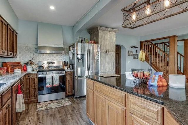 8283 345th St, Stanley, WI 54768 - kitchen with arched walkways, wall chimney exhaust hood, appliances with stainless steel finishes, wood finished floors, and backsplash