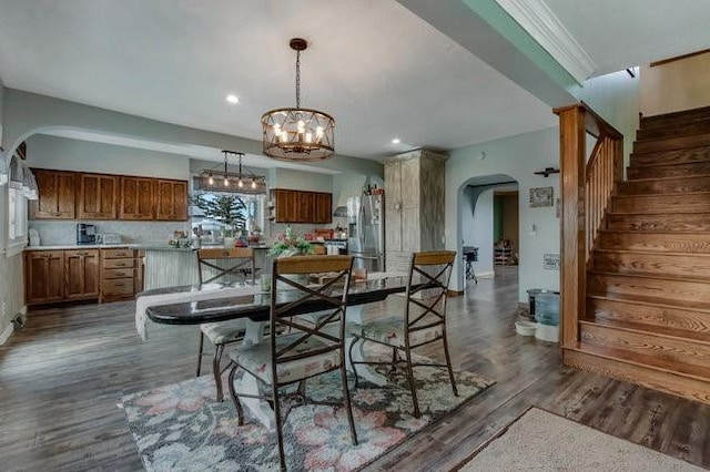 8283 345th St, Stanley, WI 54768 - dining area featuring dark wood-style flooring, ornamental molding, an inviting chandelier, stairs, and arched walkways