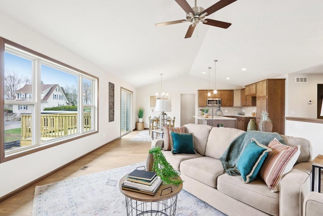 6101 Fox Run Ln, Mount Pleasant, WI 53406 - living area featuring baseboards, vaulted ceiling, light wood-style floors, visible vents, and ceiling fan with notable chandelier