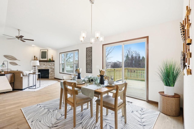6101 Fox Run Ln, Mount Pleasant, WI 53406 - dining room featuring ceiling fan with notable chandelier, a stone fireplace, light wood-type flooring, and lofted ceiling