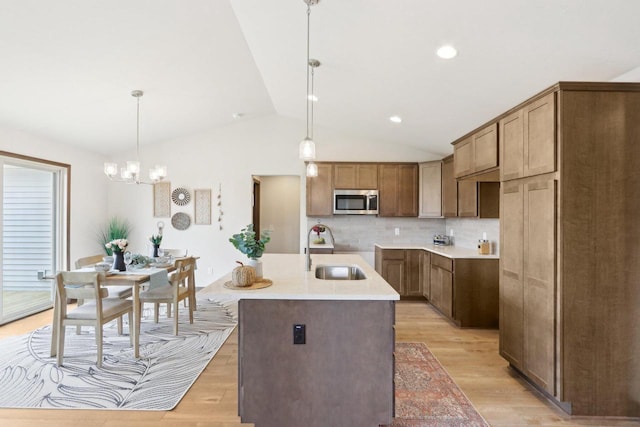 6101 Fox Run Ln, Mount Pleasant, WI 53406 - kitchen with stainless steel microwave, vaulted ceiling, decorative backsplash, light wood finished floors, and a sink