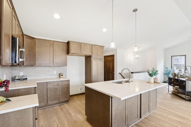 6101 Fox Run Ln, Mount Pleasant, WI 53406 - kitchen featuring stainless steel microwave, light wood-type flooring, a sink, and decorative backsplash