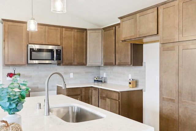 6101 Fox Run Ln, Mount Pleasant, WI 53406 - kitchen featuring stainless steel microwave, vaulted ceiling, backsplash, decorative light fixtures, and a sink