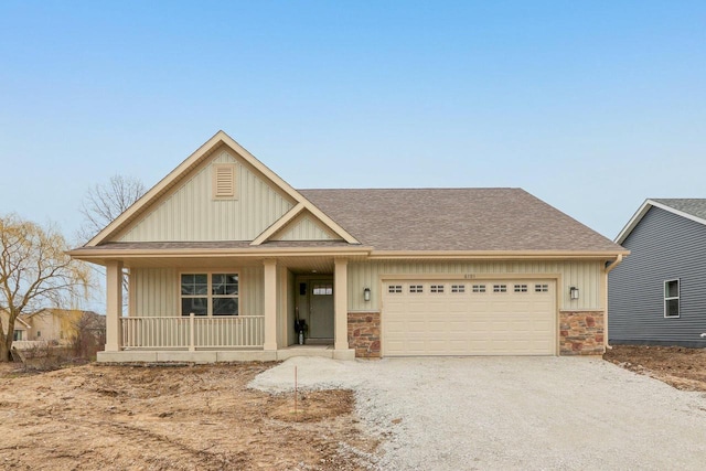 6101 Fox Run Ln, Mount Pleasant, WI 53406 - view of front facade with board and batten siding, covered porch, stone siding, an attached garage, and driveway