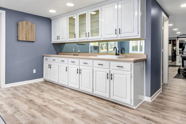 N4455 Dorothy Jane Ct, Kaukauna, WI 54130 - kitchen featuring baseboards, glass insert cabinets, white cabinetry, light wood-style floors, and a sink