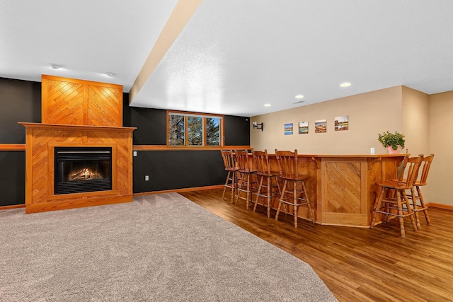9842 Elan Rd, Tomah, WI 54660 - indoor bar with wood finished floors, baseboards, recessed lighting, and a glass covered fireplace