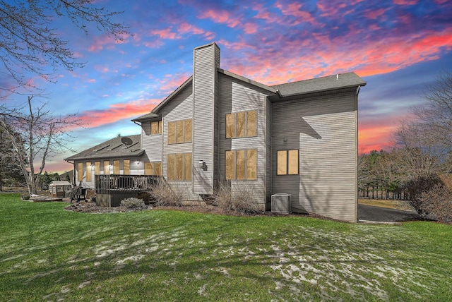 9842 Elan Rd, Tomah, WI 54660 - back of property at dusk featuring a chimney, a yard, a wooden deck, and central AC unit