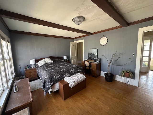 bedroom with wood-type flooring, beamed ceiling, and wooden walls