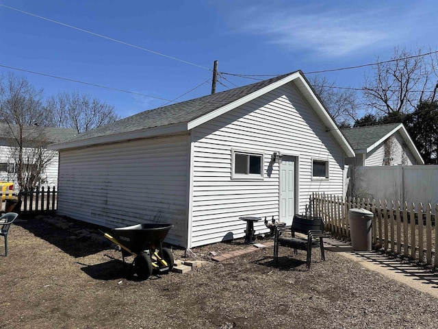 rear view of property featuring fence and a shingled roof