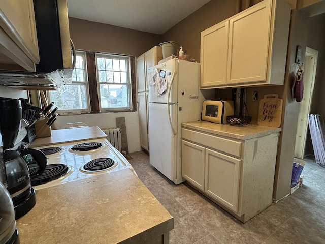 kitchen with radiator heating unit, light countertops, freestanding refrigerator, and white cabinetry