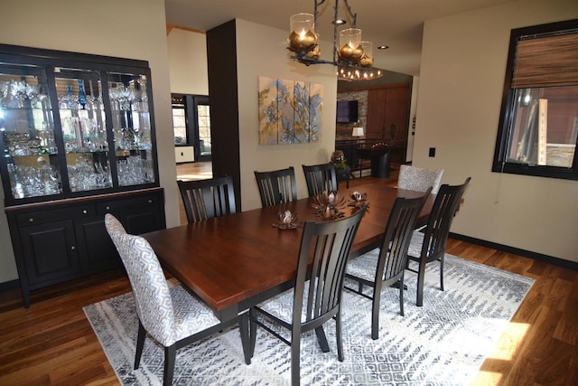 dining space featuring a chandelier, baseboards, and wood finished floors