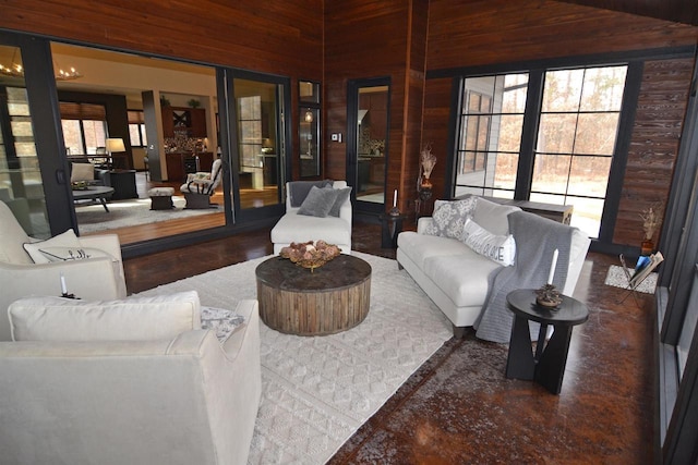 living area with a high ceiling, wooden walls, and plenty of natural light