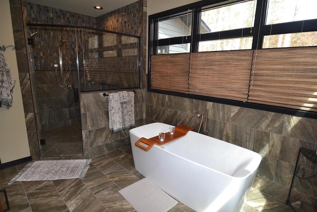full bath featuring a soaking tub, tile walls, and a stall shower
