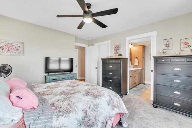 bedroom featuring light carpet, ensuite bathroom, and ceiling fan