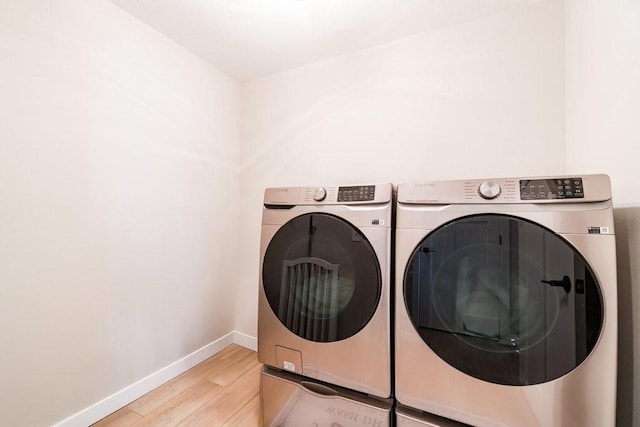 laundry area featuring washer and dryer, laundry area, baseboards, and wood finished floors